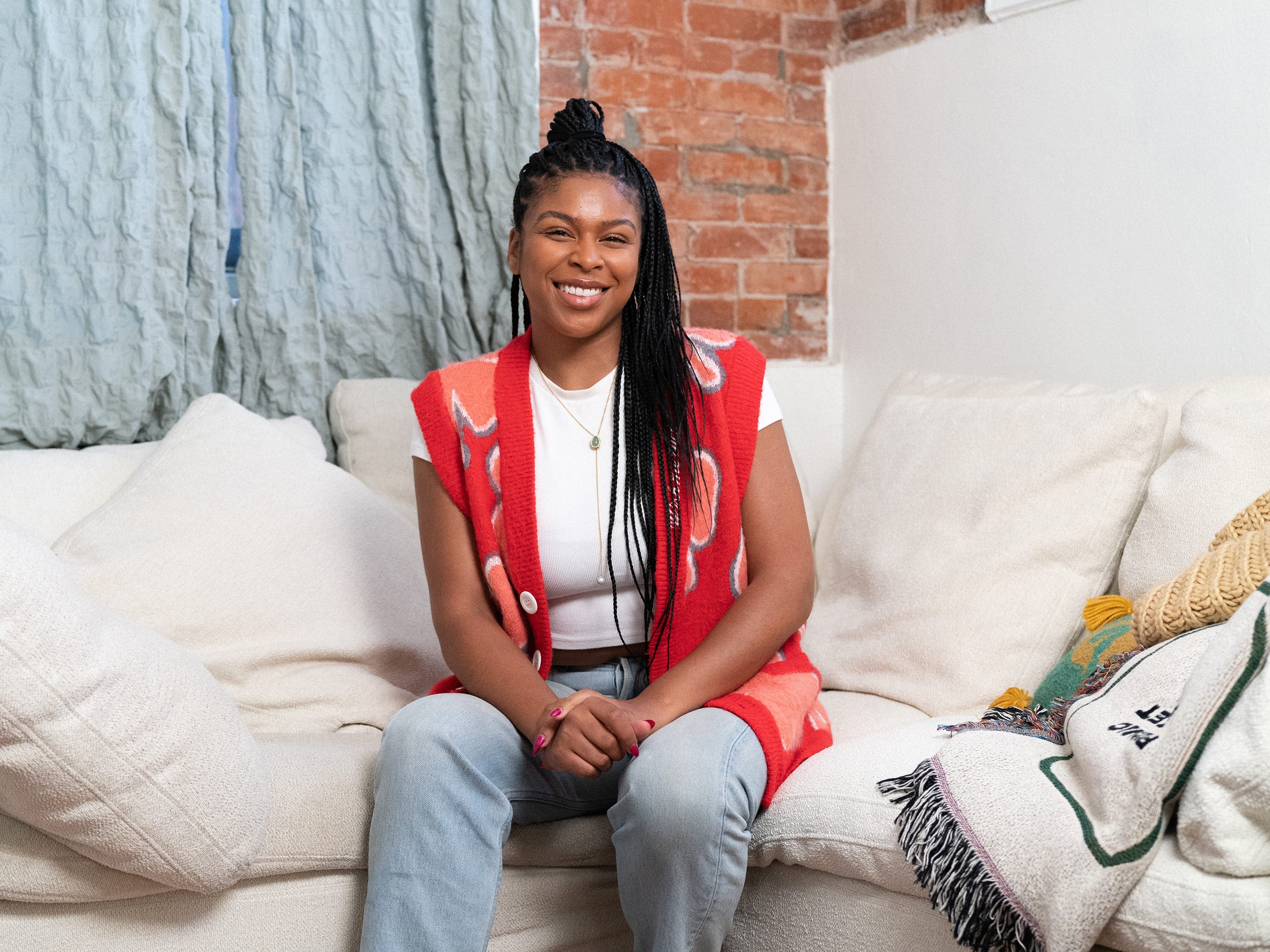 Darian Symone Harvin, editor, seated on a couch, facing the camera.