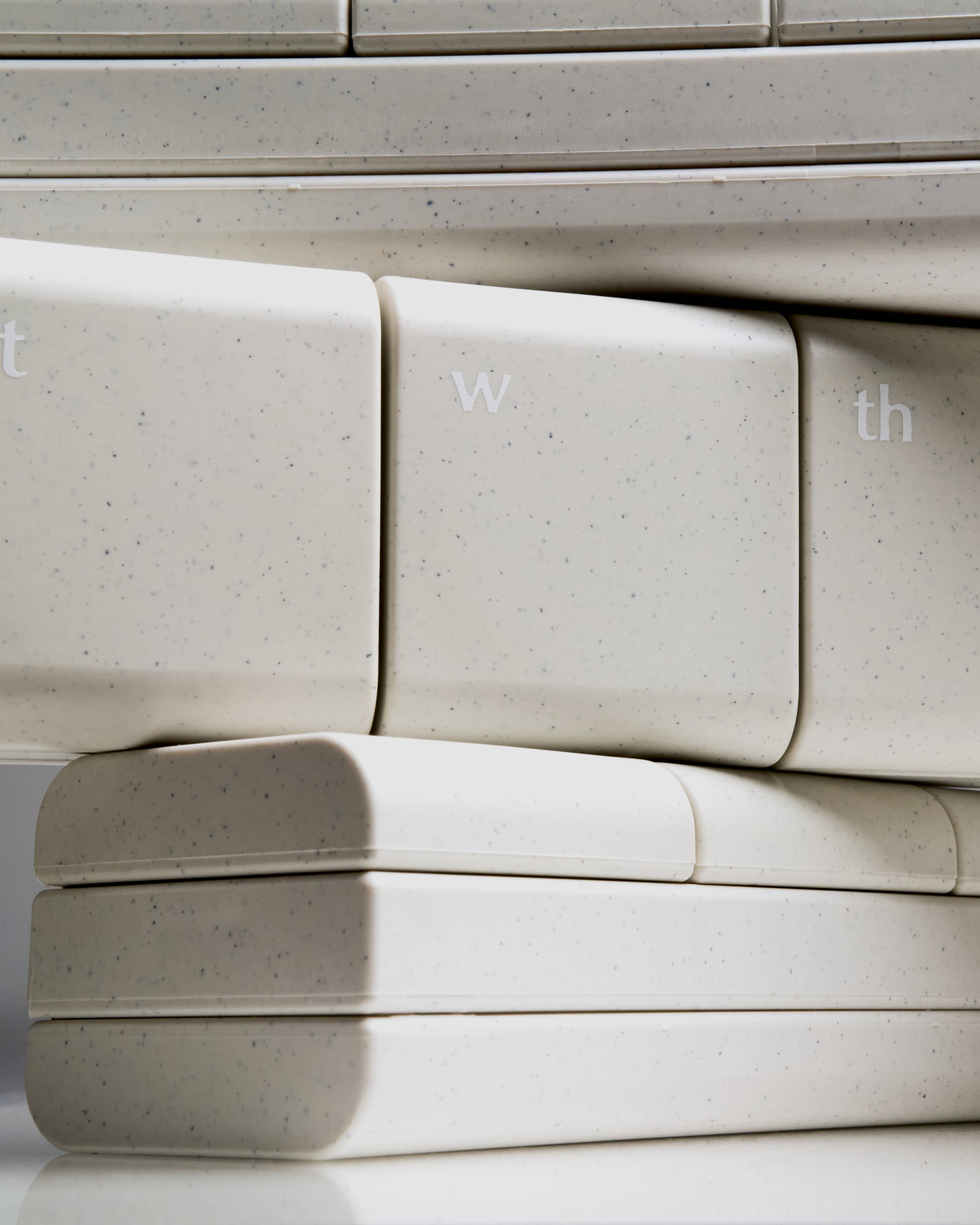 AndAgain 7-Day Pill Box in Original speckled cream color, standing upright with sleek design and capsules scattered—designed for modern daily wellness and supplements.