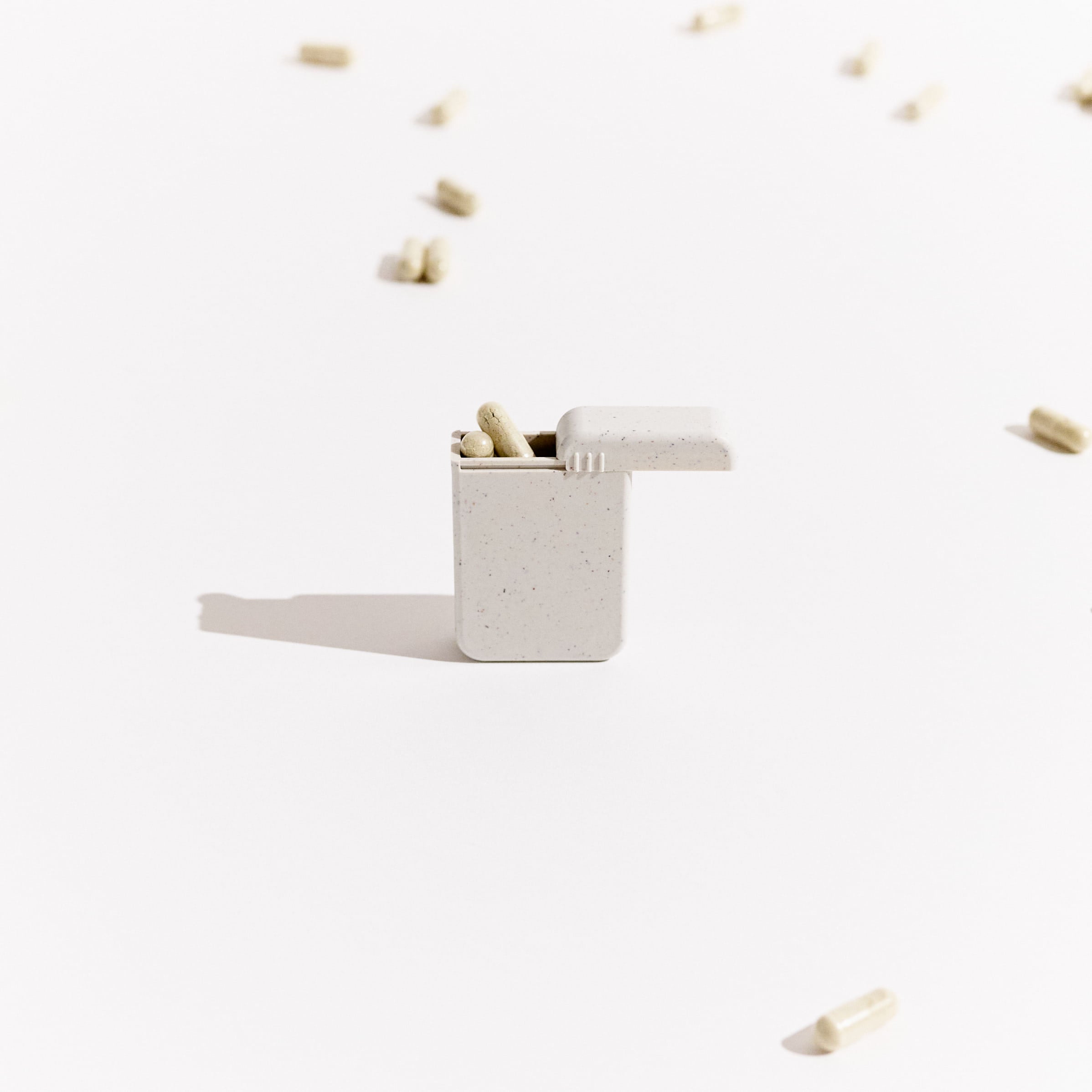 AndAround travel pill case with supplements spilling out, a sleek and minimalist way to store pills on the go.