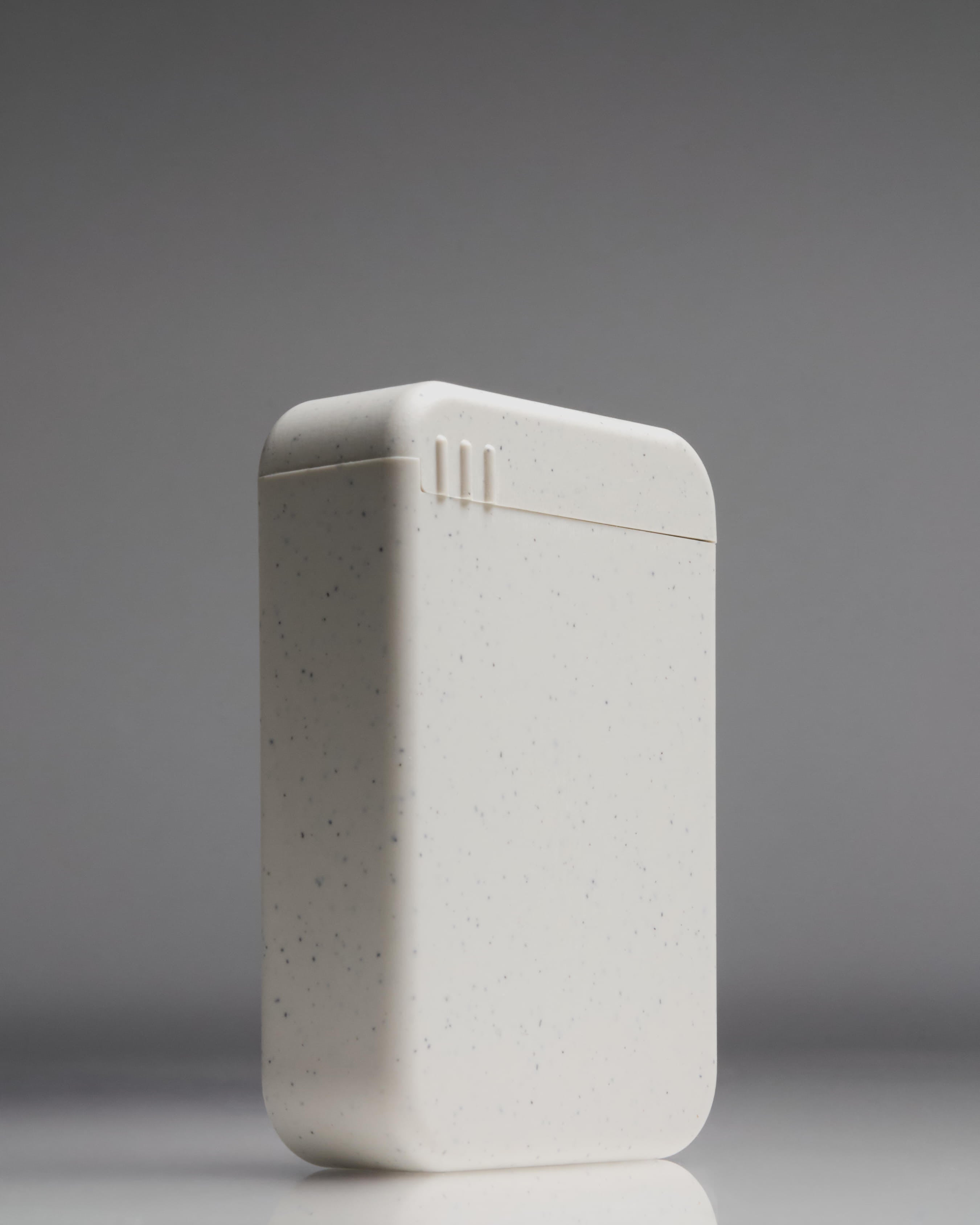 Closed AndAround pill case standing upright—minimal speckled design for carrying pills and supplements while traveling.
