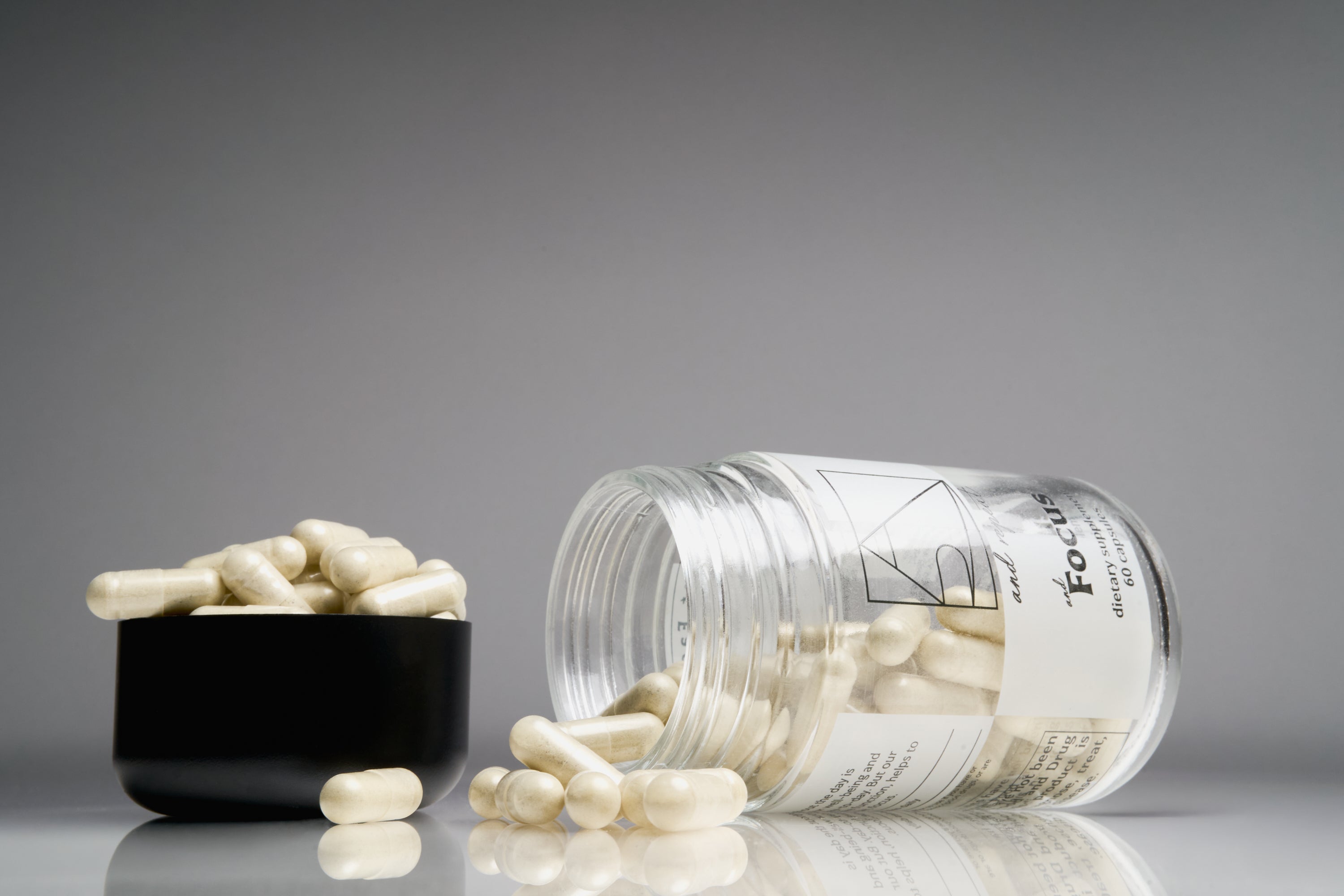 A jar of AndFocus daily focus supplement open on its side with pills pouring out, and pills in the cap.