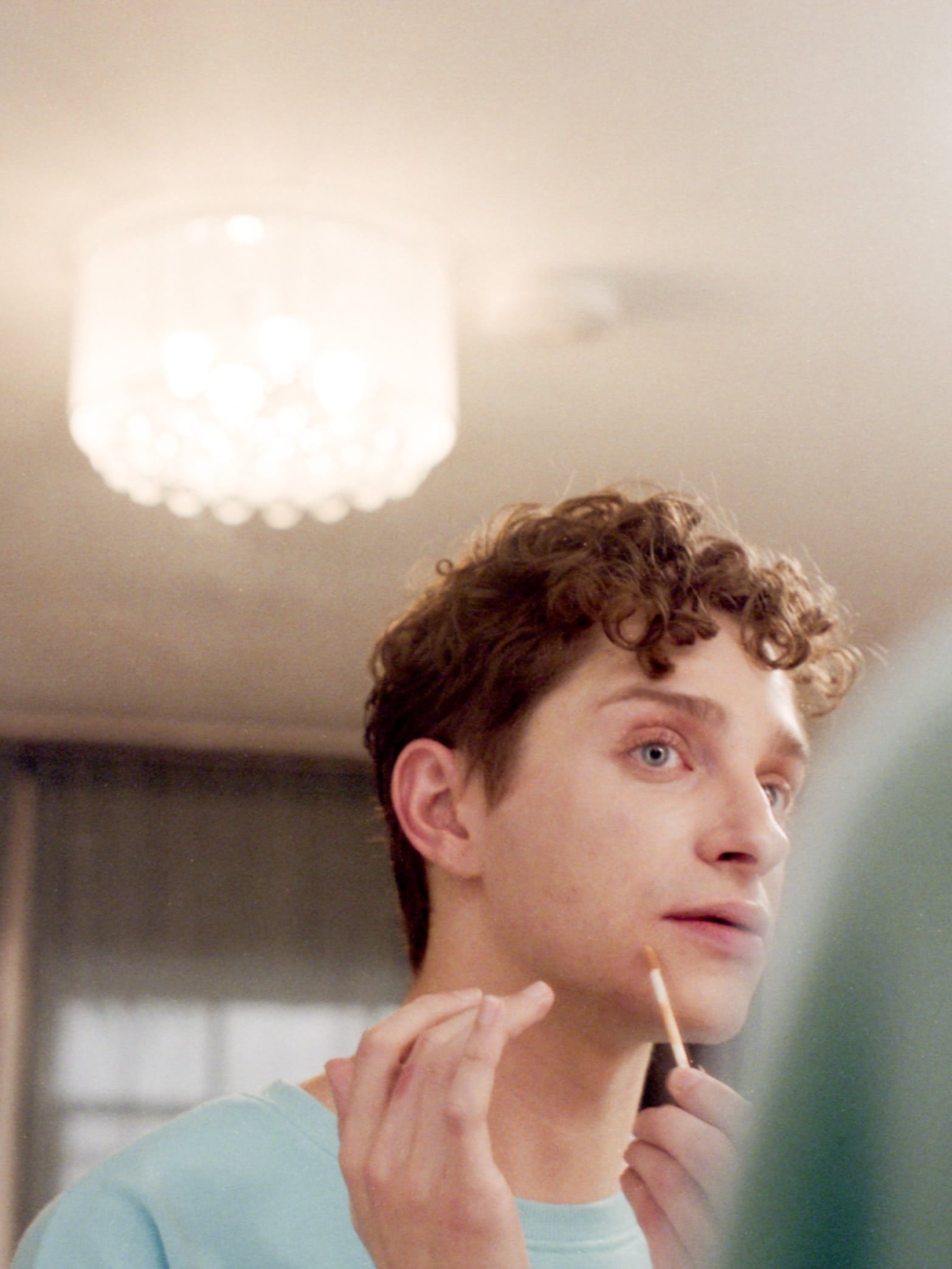 Actor Dino Petrera, sitting in front of a mirror putting on makeup