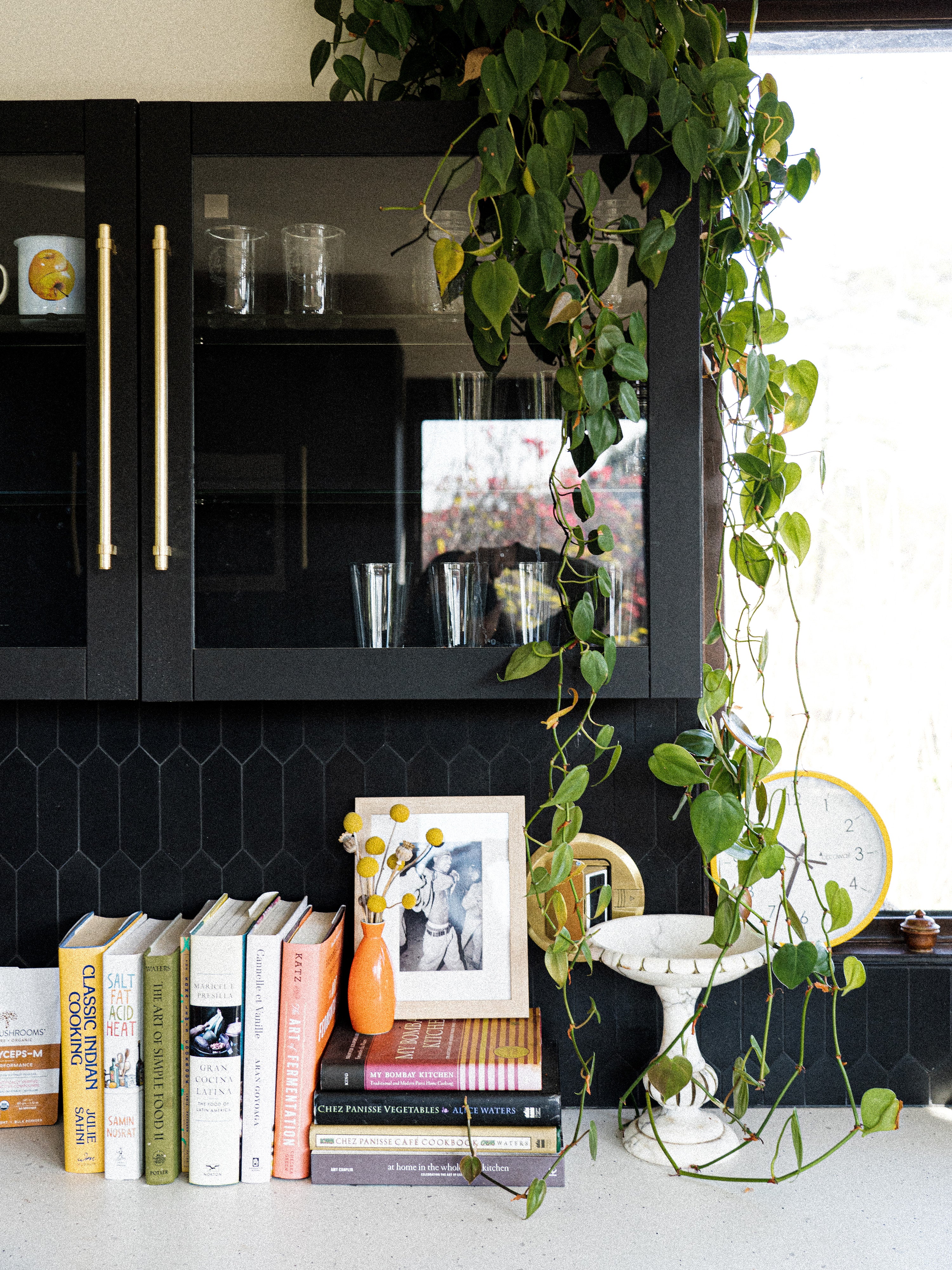 Kacie Carter, chef and co-founder of Honey Hi and holistic nutritionist's kitchen counter with plants, flowers and cookbooks