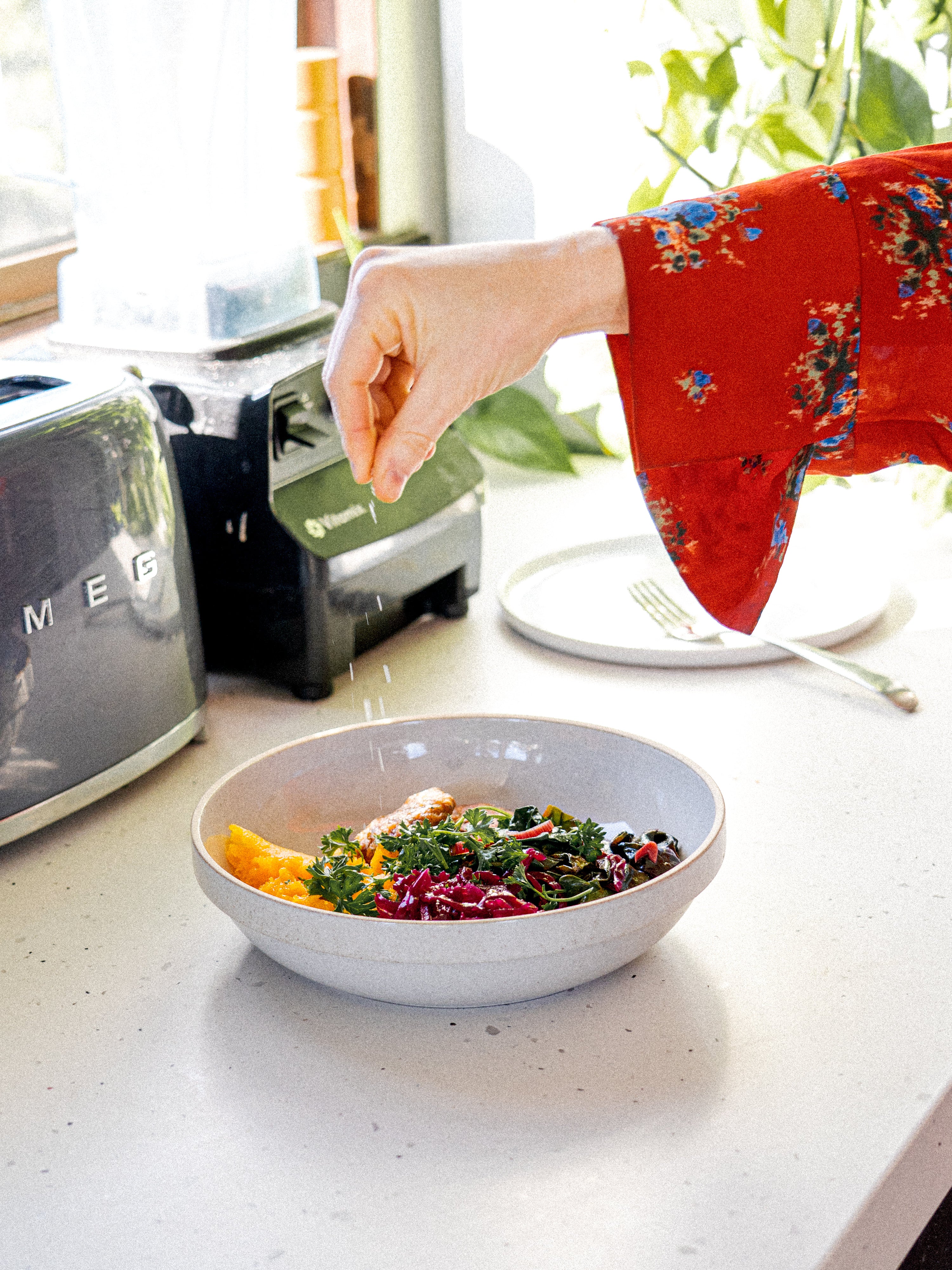 Kacie Carter, chef and co-founder of Honey Hi and holistic nutritionist sprinkling salt onto a bowl of food