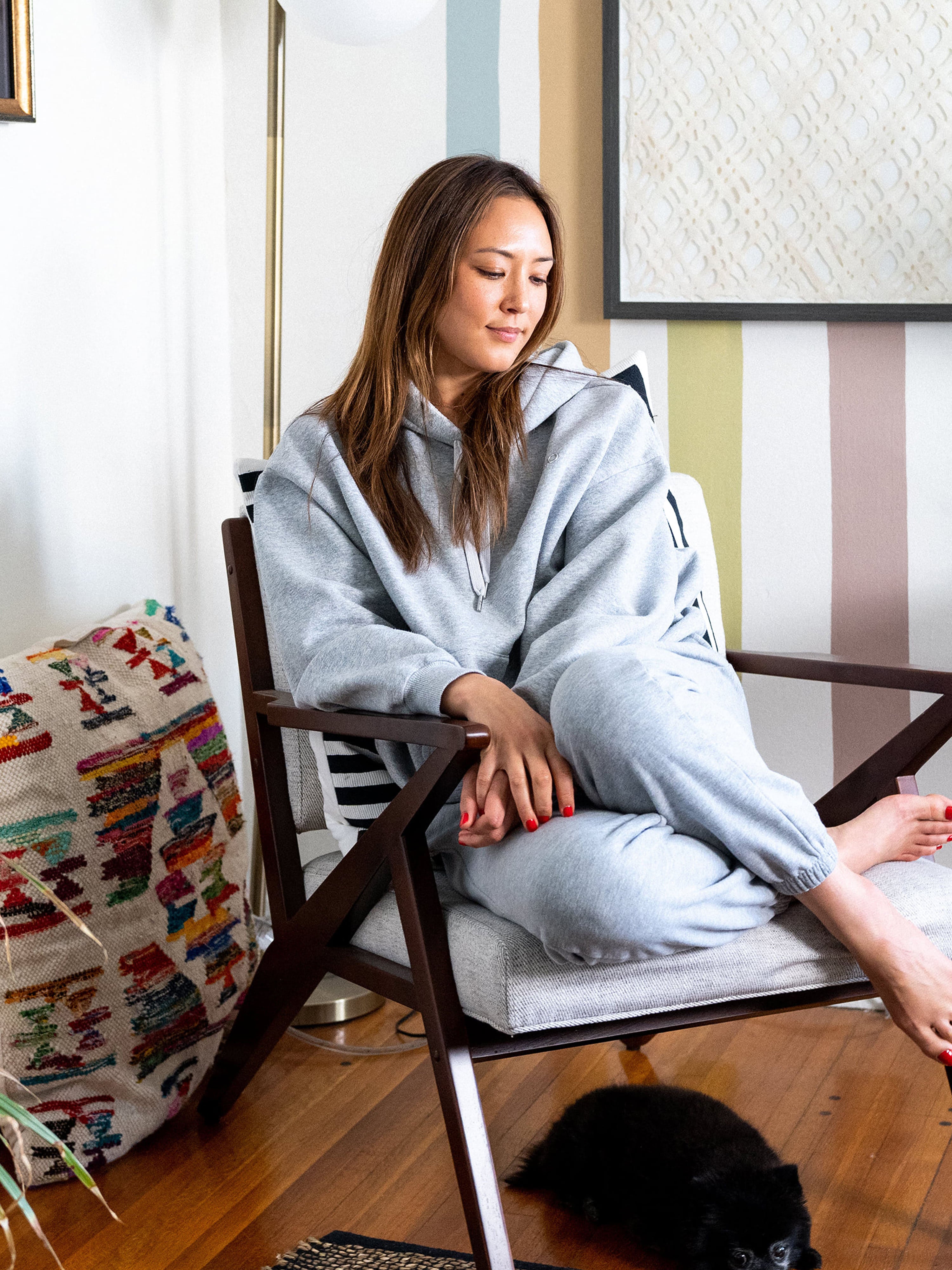 Aesthetician Sora Connor sitting in a chair in her living room looking down.