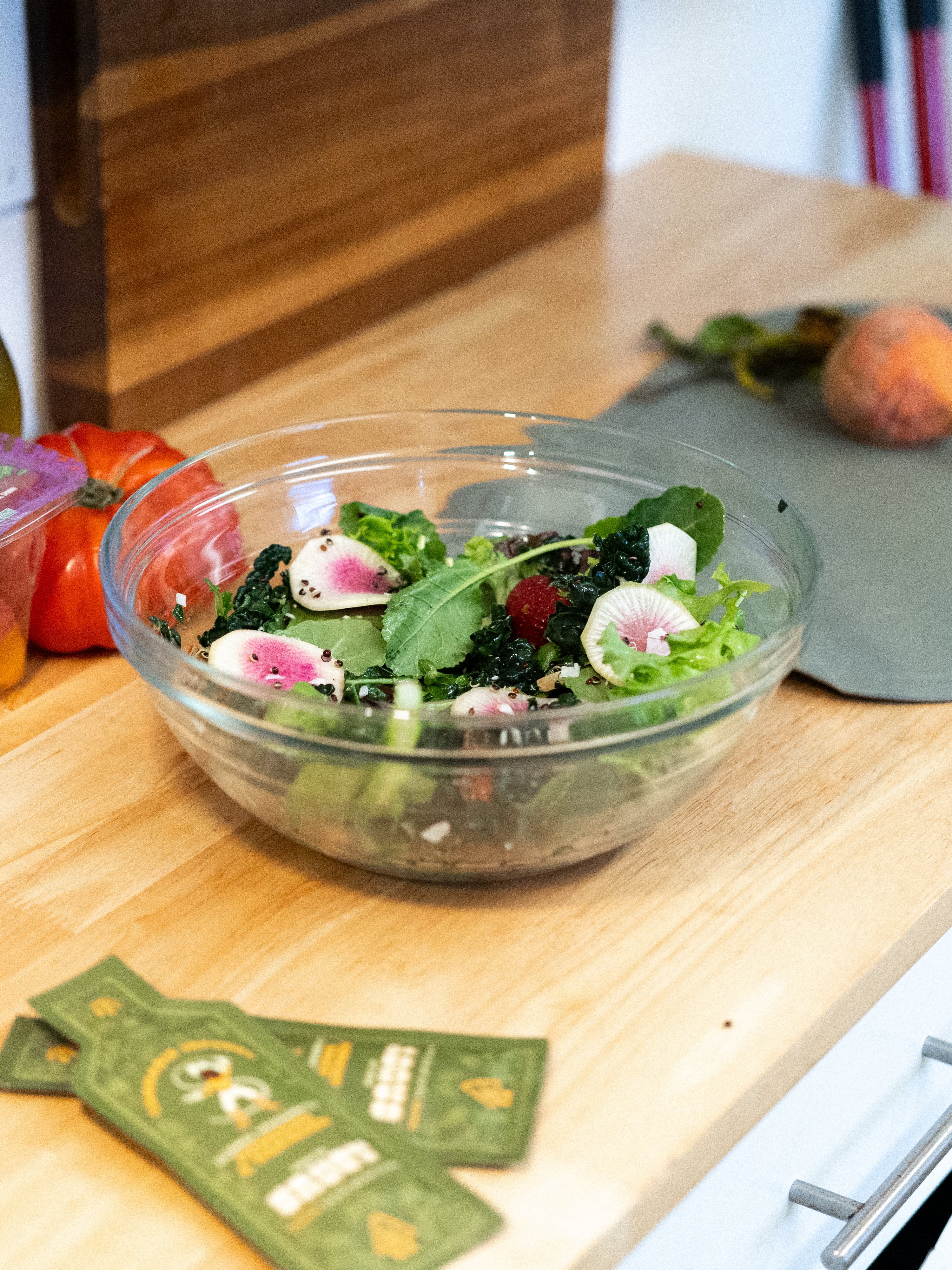 A salad on a kitchen table, along with saucy bbq sauce and some vegetables