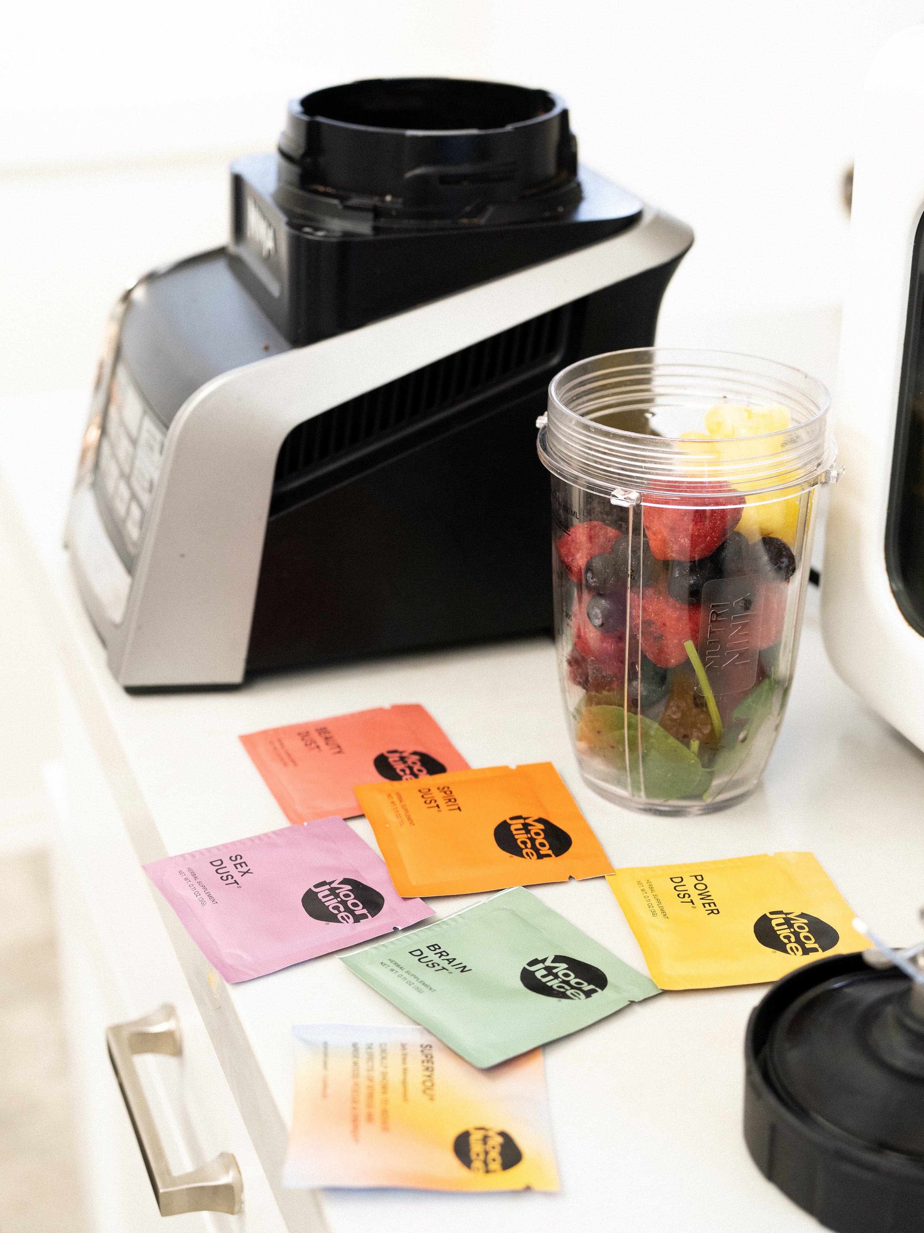 Tess Taylor's smoothie & supplements, ingredients such as fruit and Moon Juice packets, laid out on her kitchen table