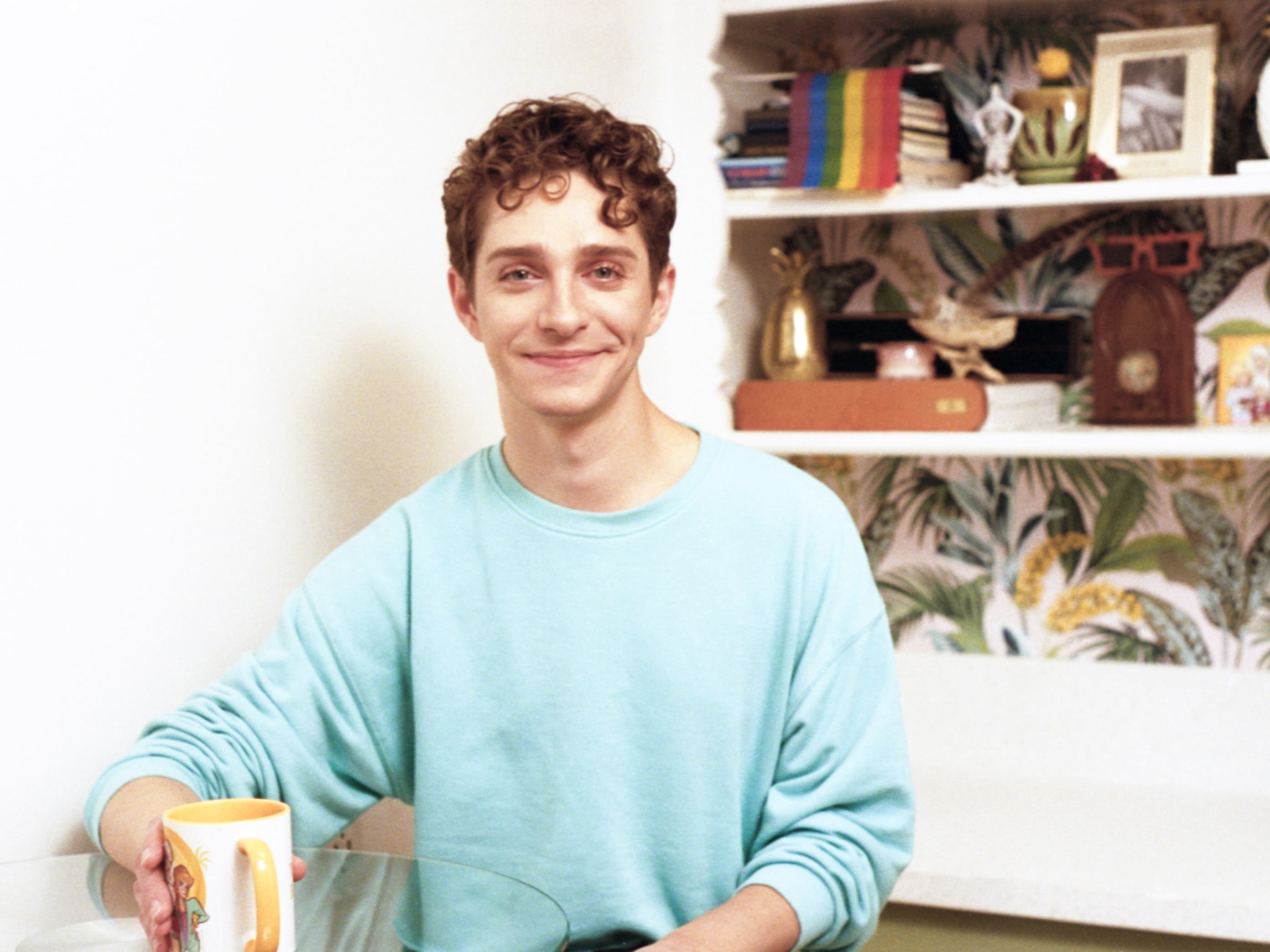 Actor Dino Petrera, sitting in his kitchen with a cup of coffee in his hand