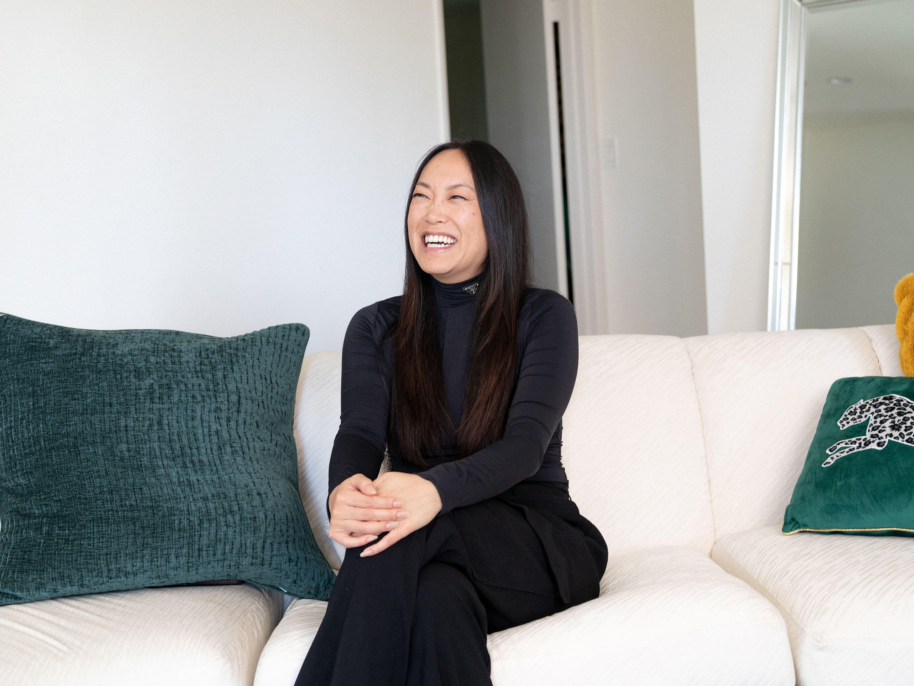The publicist and founder of SixTen PR, Jen Woodward, smiling while sitting on her living room couch