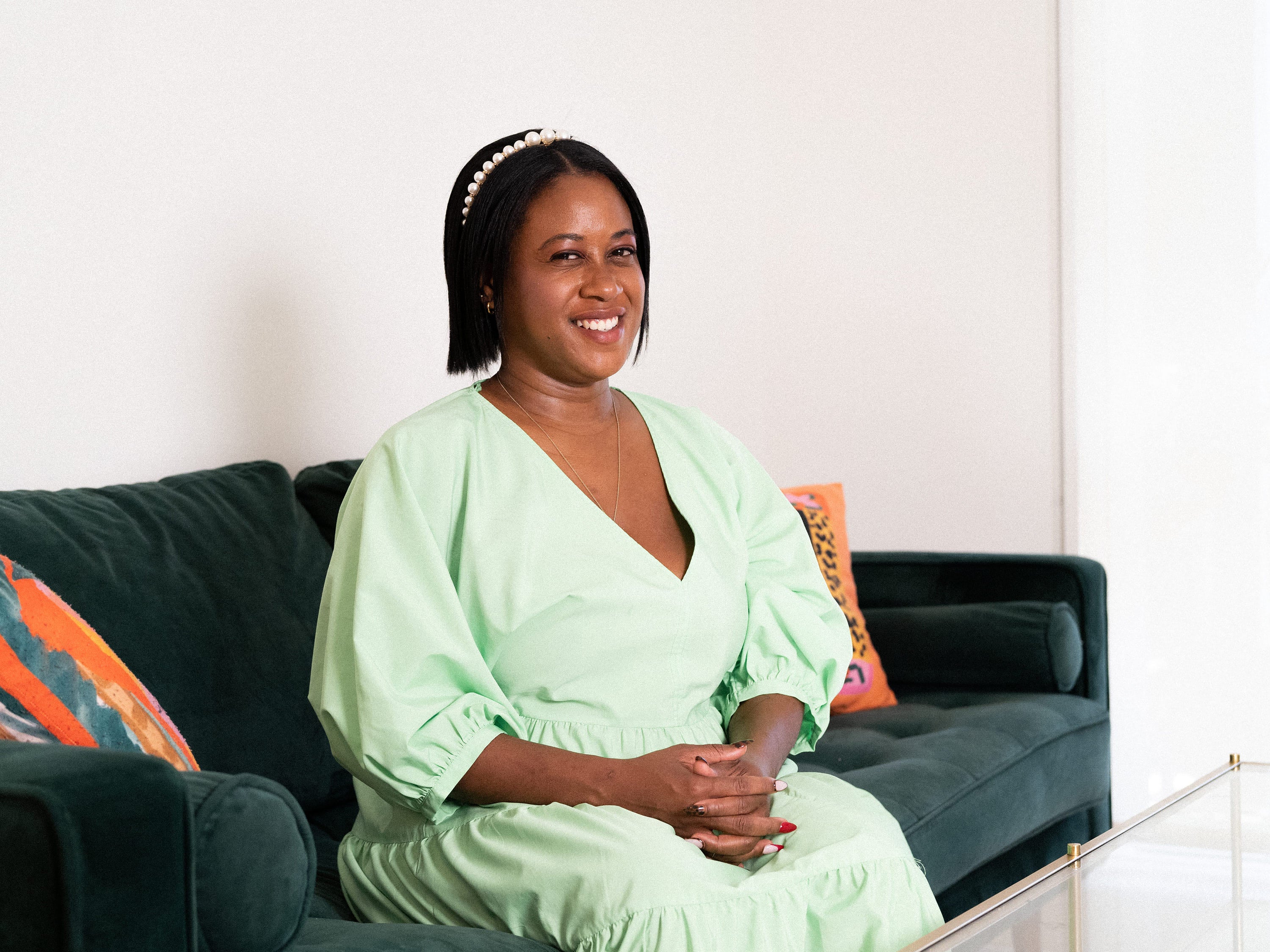 Maryam Ajayi, the founder of Dive in Well, sitting on her green couch and smiling.