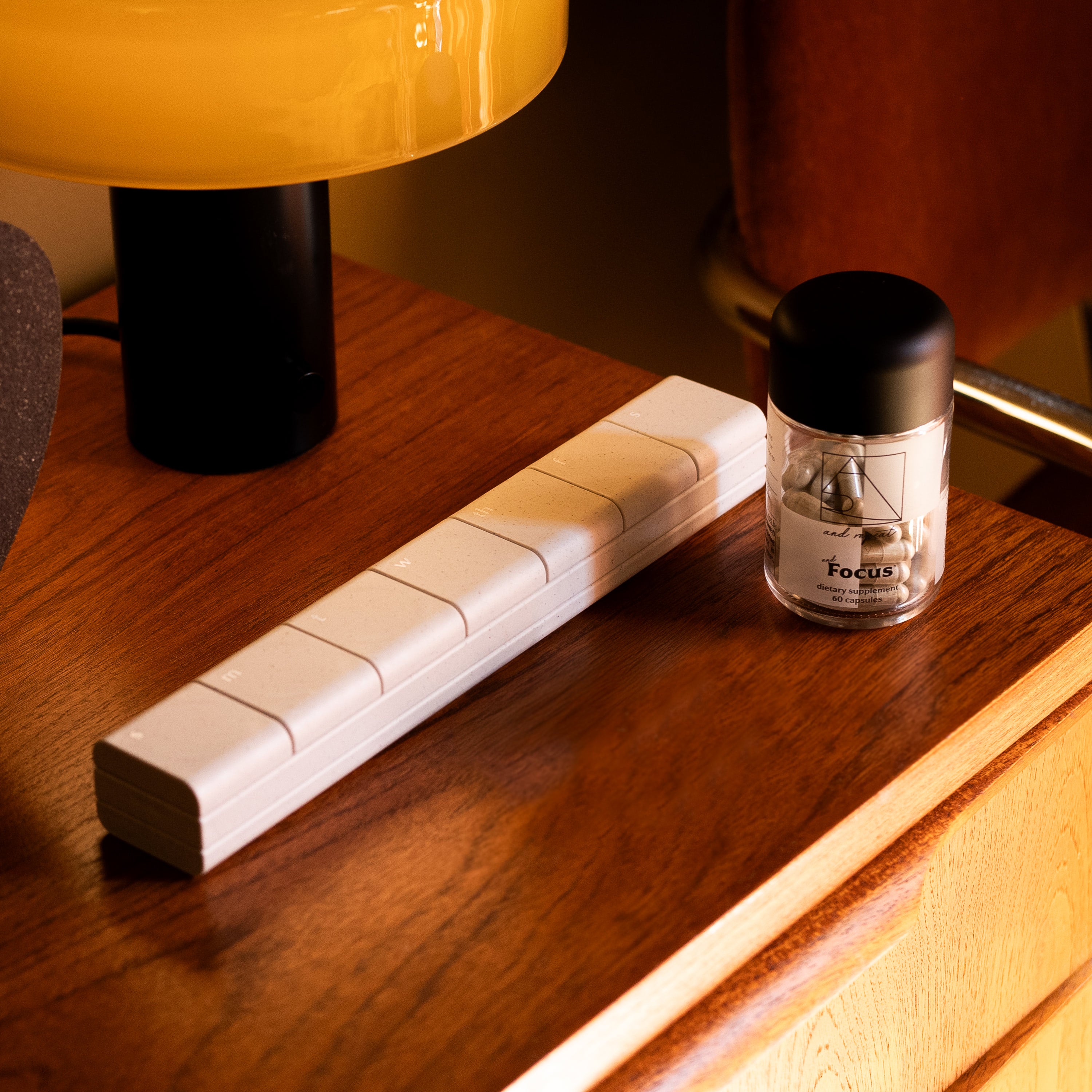 AndBundle 1.0 with AndAgain 7-Day Pill Case and AndFocus daily supplement resting on a wood table, a modern solution for supplement organization.