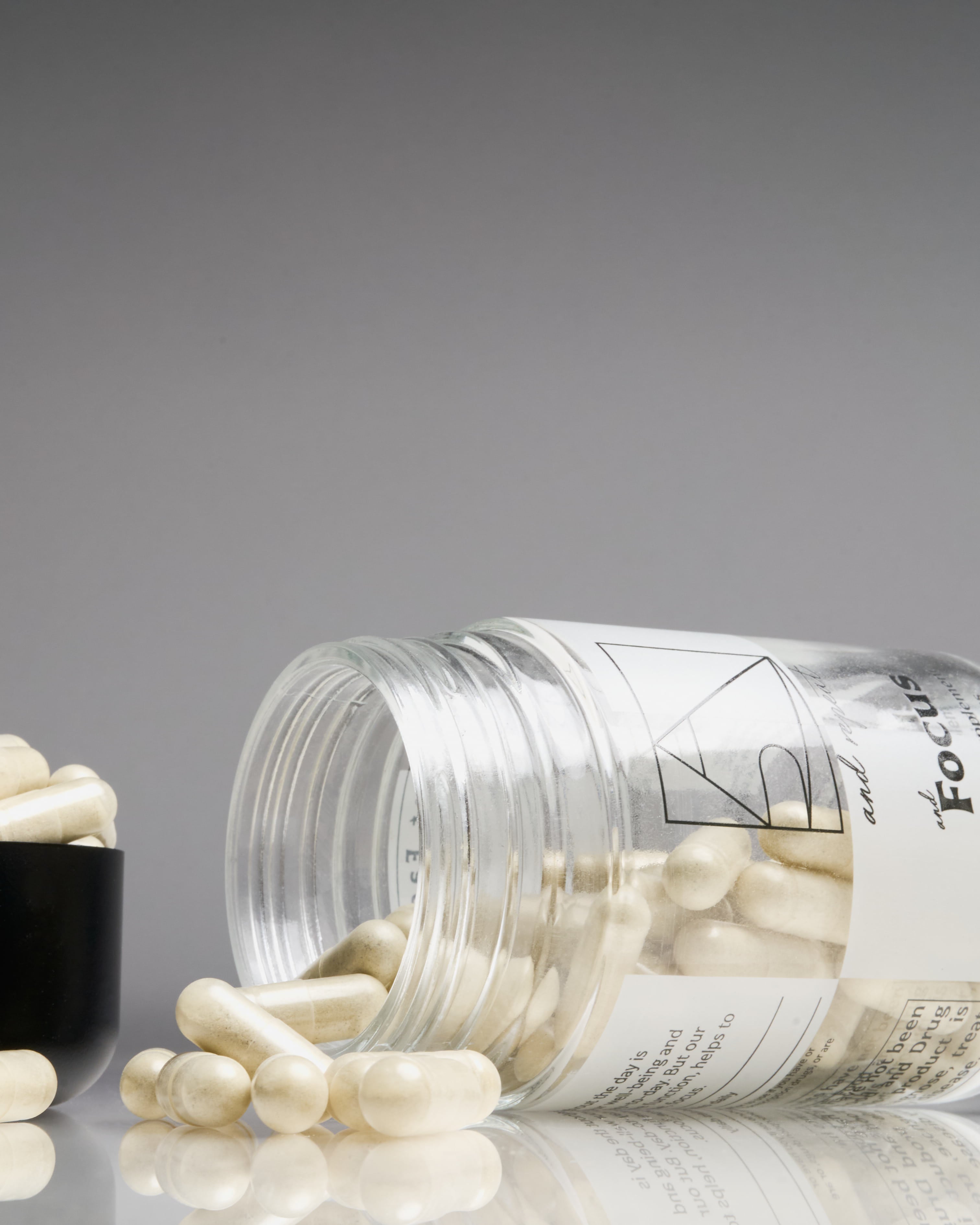 Close-up of AndFocus supplement bottle on seamless background with capsules spilling out—vegan, organic formula for mental clarity and presence.