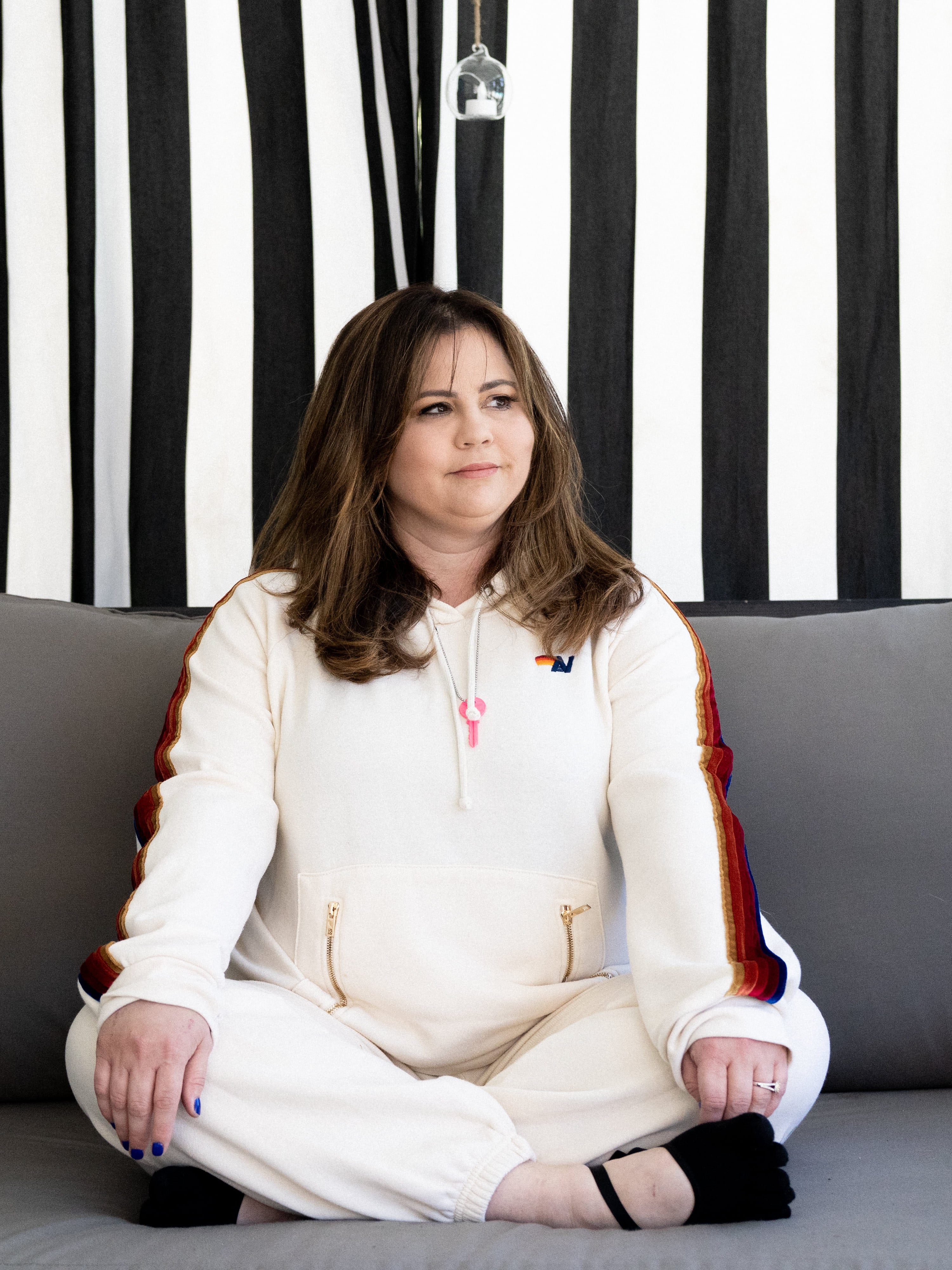 Mandy Teefey sitting on a grey couch looking off to her side