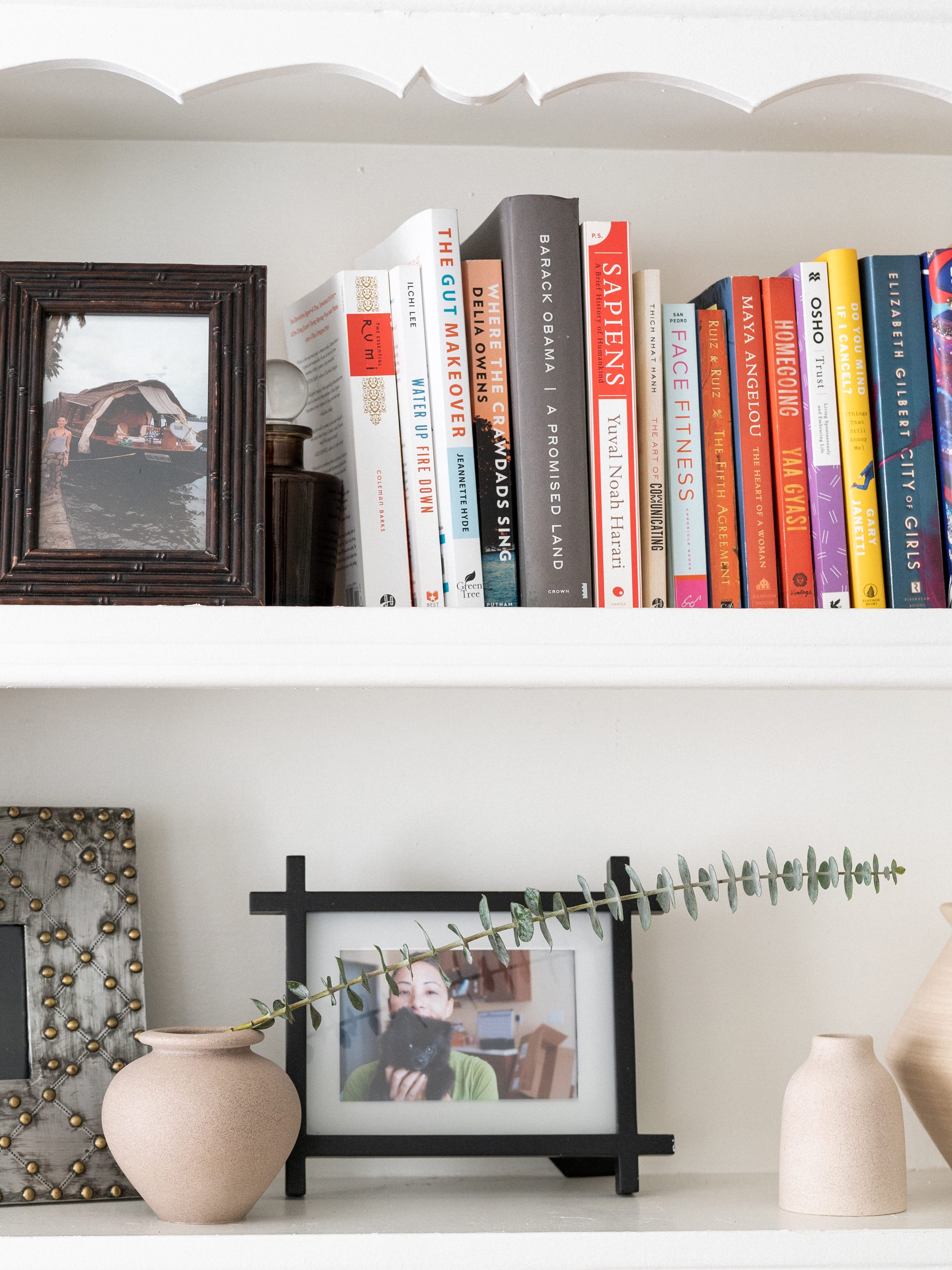 Aesthetician Sora Connor's bookshelf with books, pottery and picture frames.