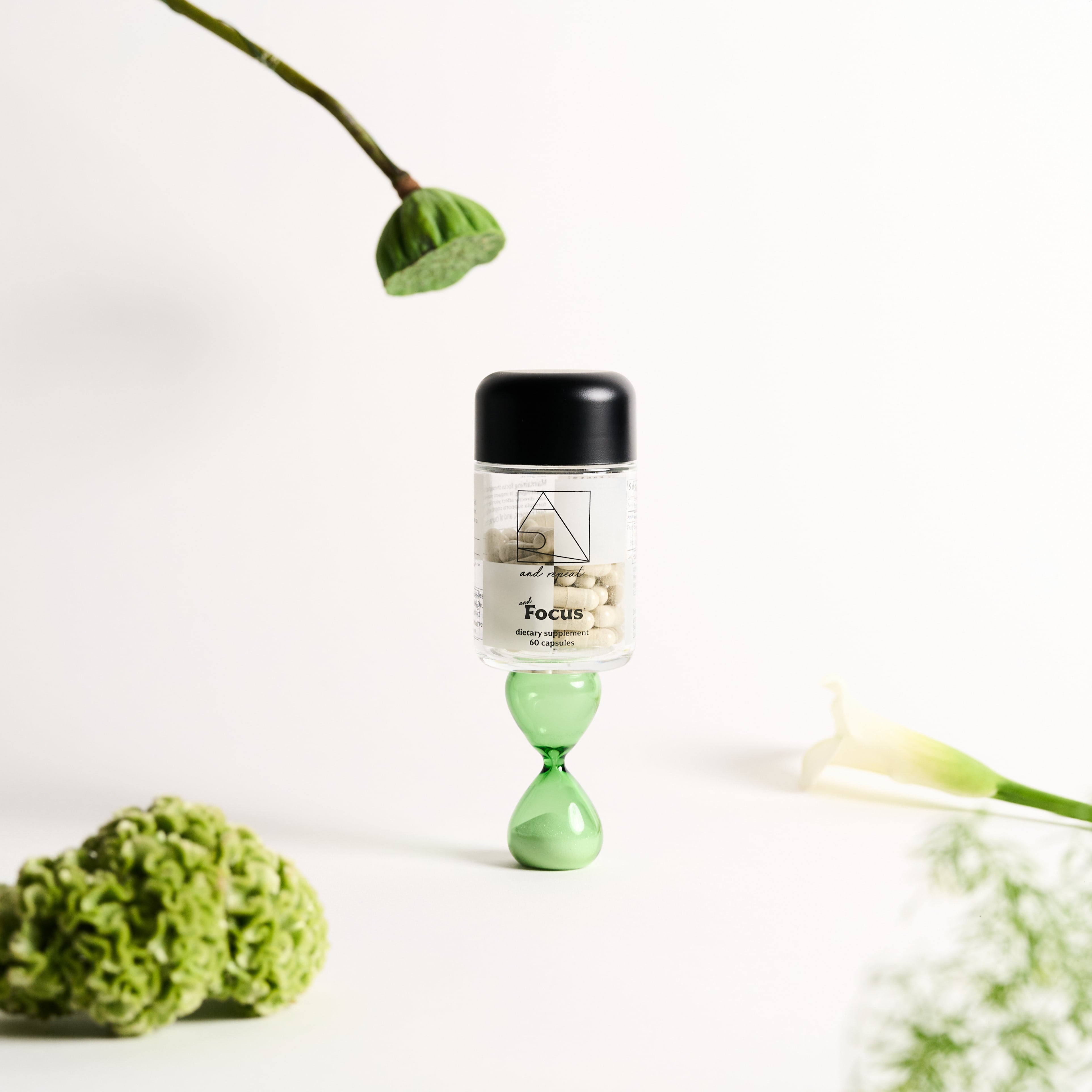AndFocus daily supplement jar placed on an hourglass, surrounded by greenery, symbolizing balance, focus, and cognitive support.
